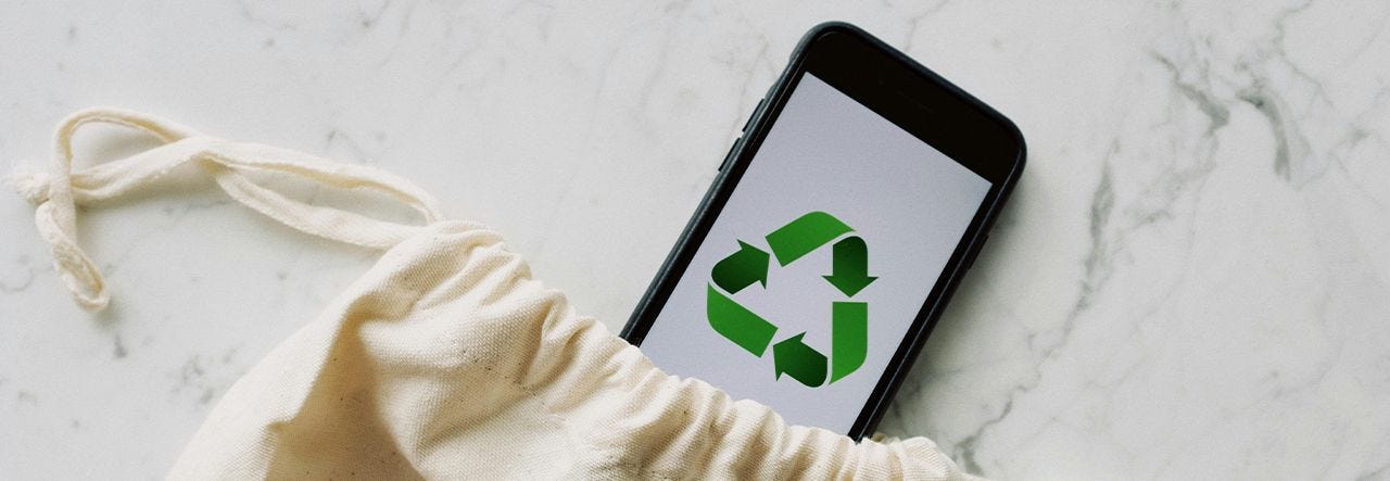 phone with recycling triangle symbol poking out of canvas bag
