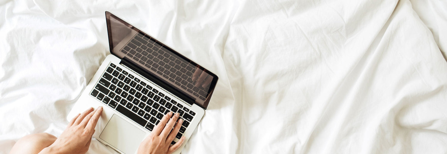 person researching trends on laptop in bed
