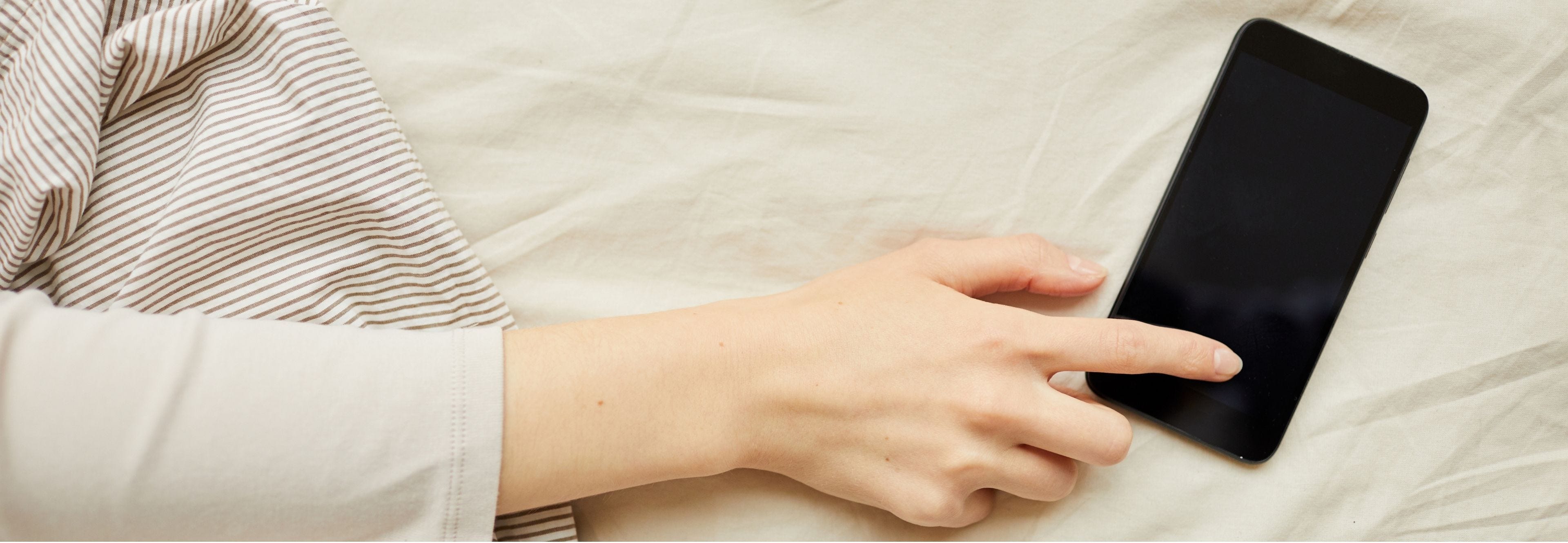 hand reaching for cell phone in bed