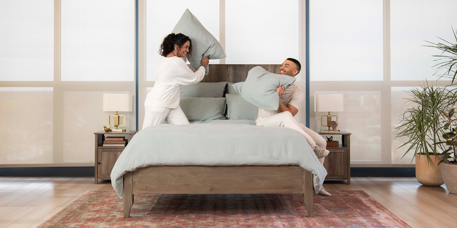 couple pillow fighting with linen bedding