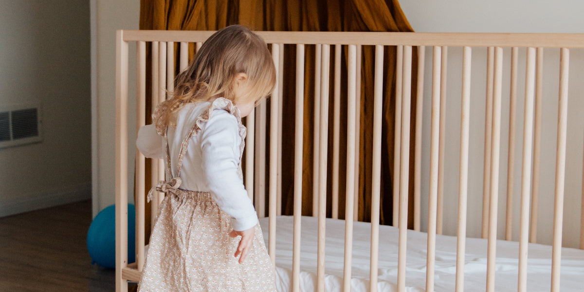 toddler girl standing by toddler bed
