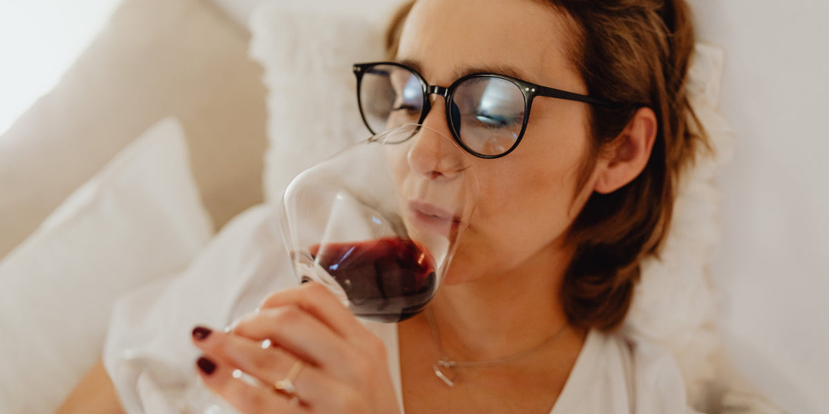 Woman drinking glass of wine in bed