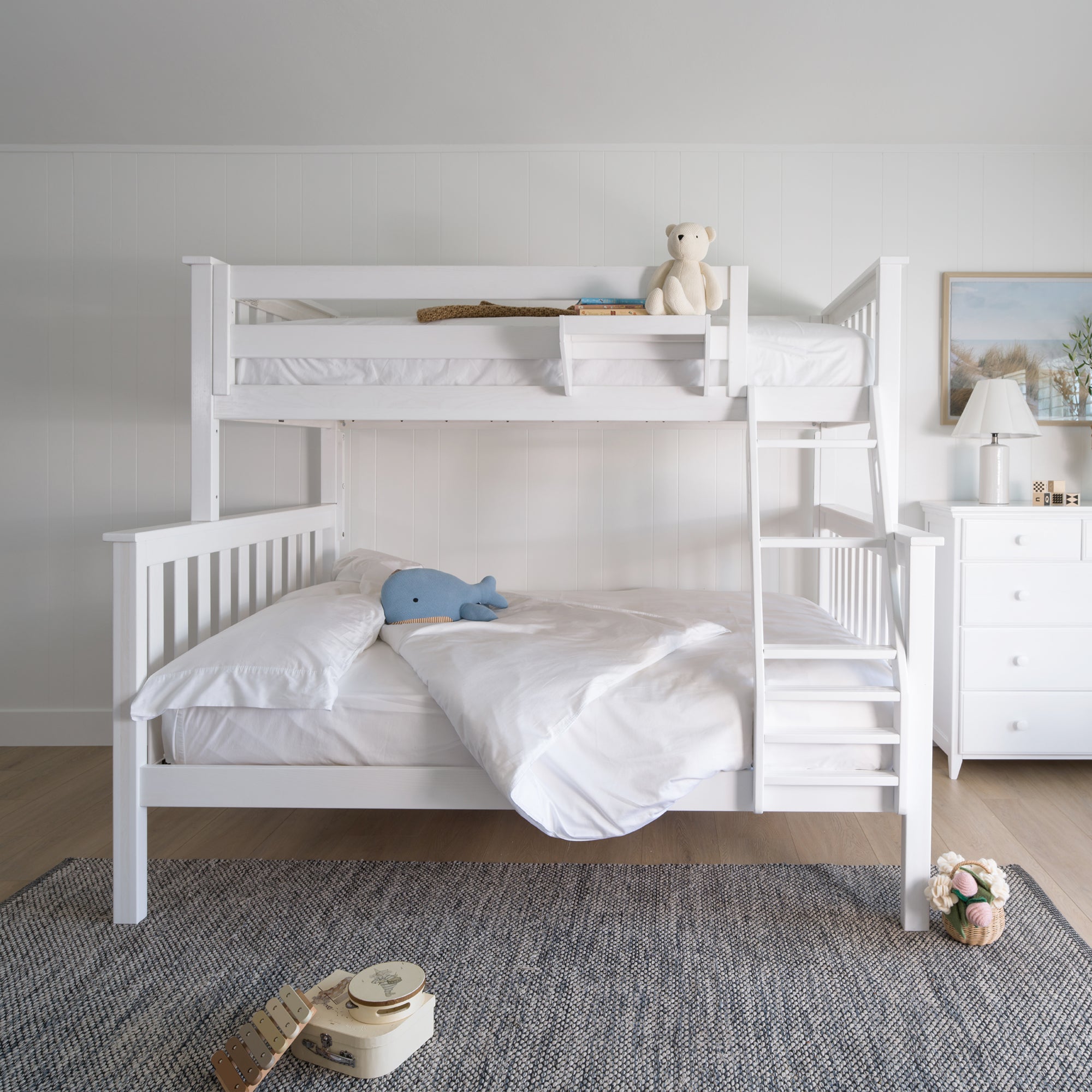White bunk bed in a room with toys and a dresser. #color_washed white #size_Twin/Full Bunk
