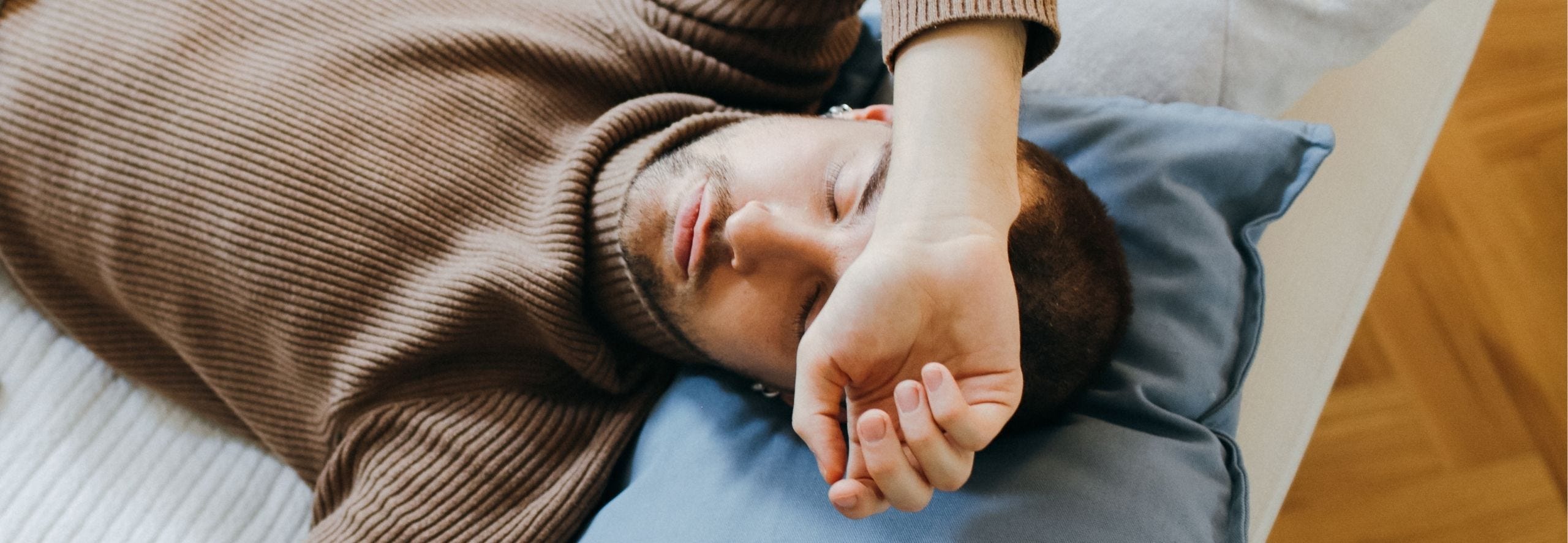 man sleeping on the couch with arm draped across forehead