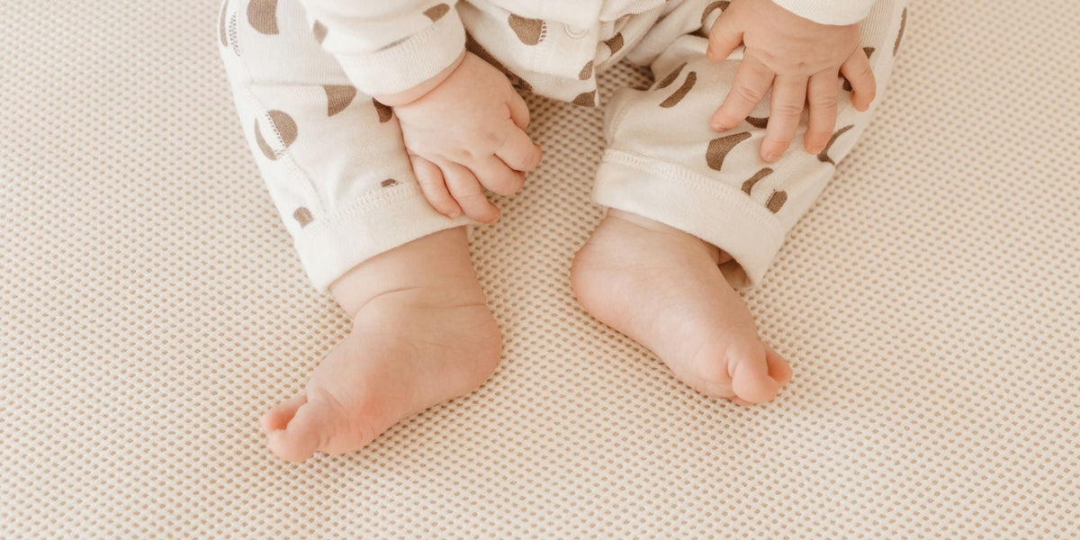 Image of Naturepedic breathable crib mattress with baby feet and hands at the top of the image