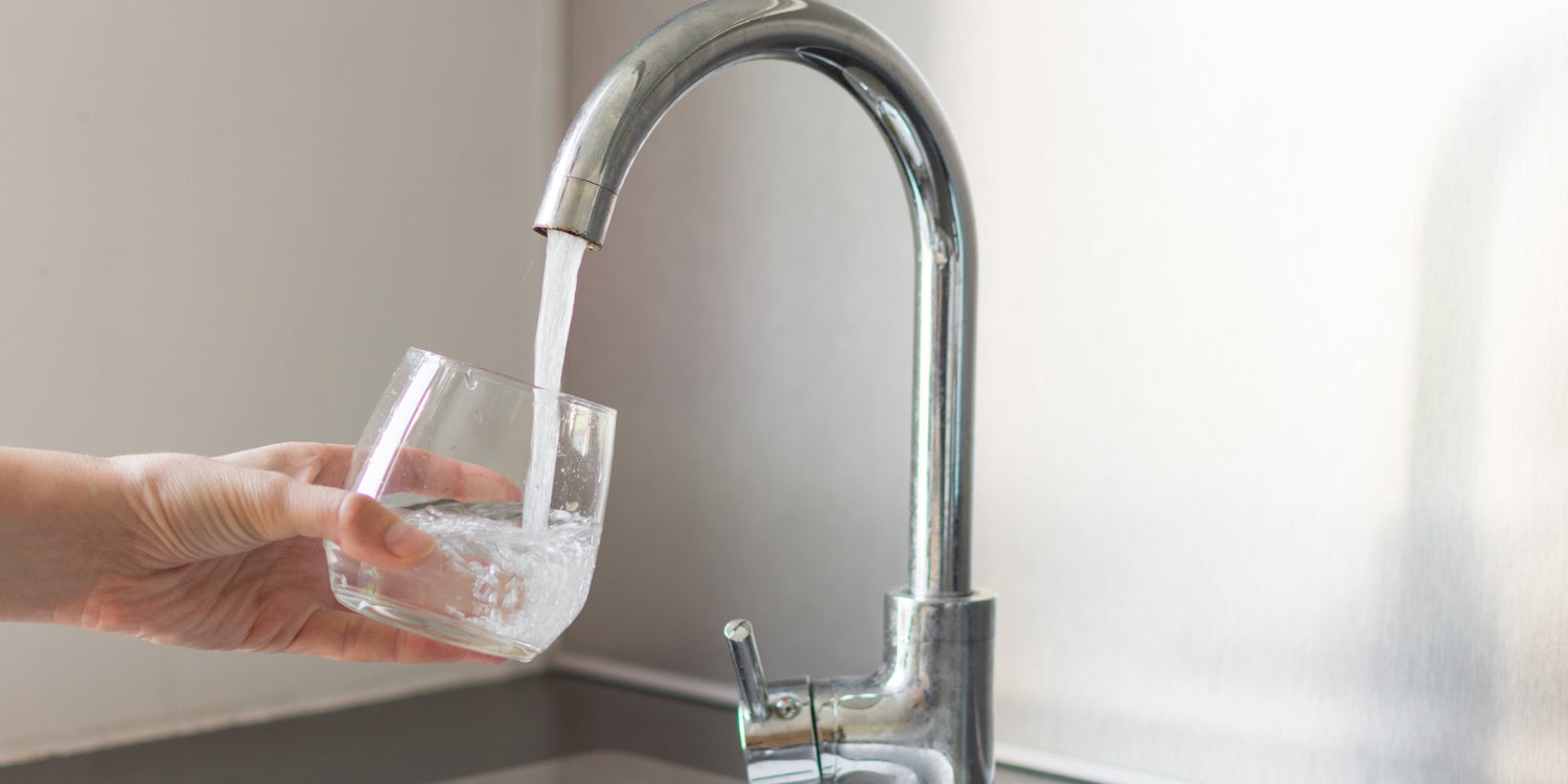 Hand filling glass with tap water