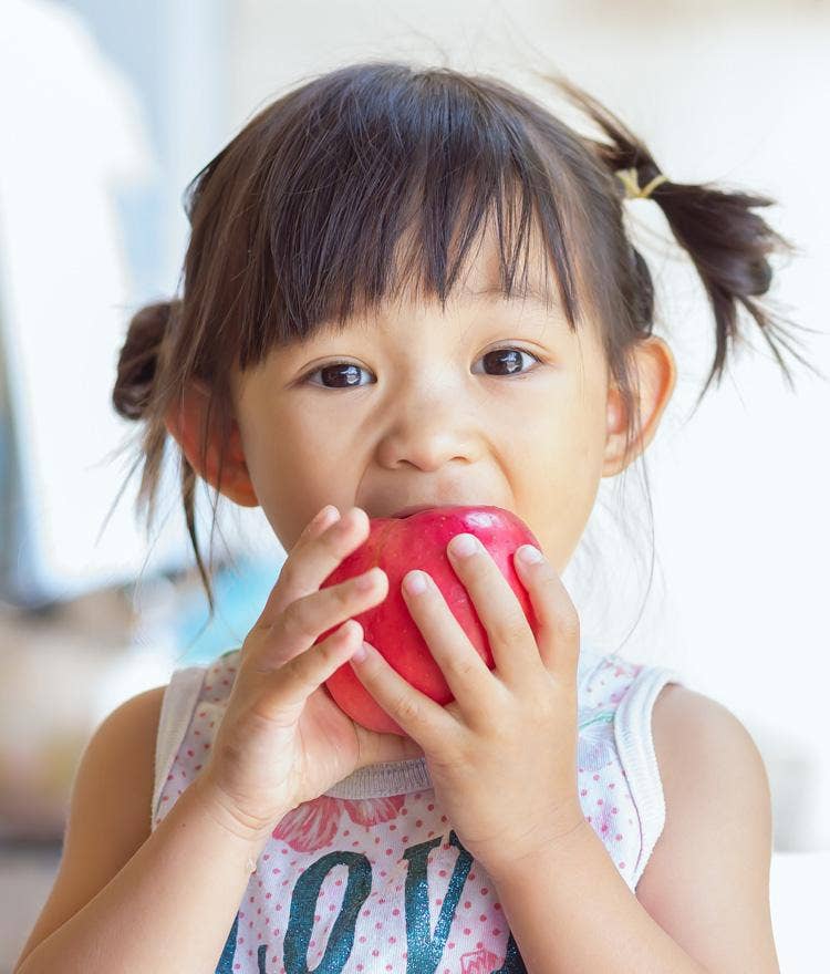 Young girl biting into a red apple