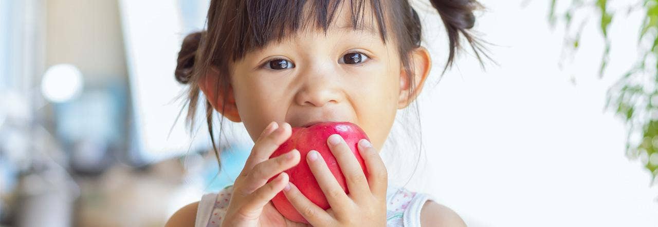 Young girl biting into a red apple