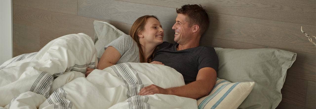 Woman and man smiling at each other in bed
