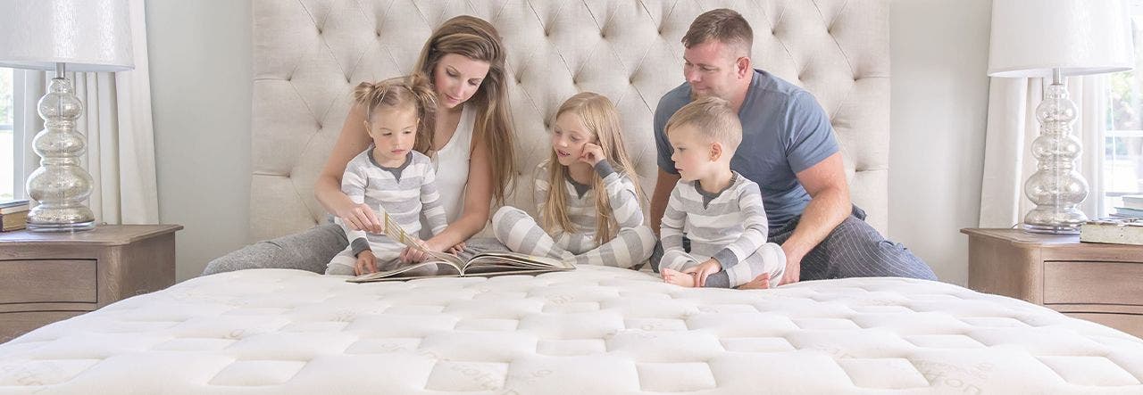 Family of five reading together on a Naturepedic organic mattress