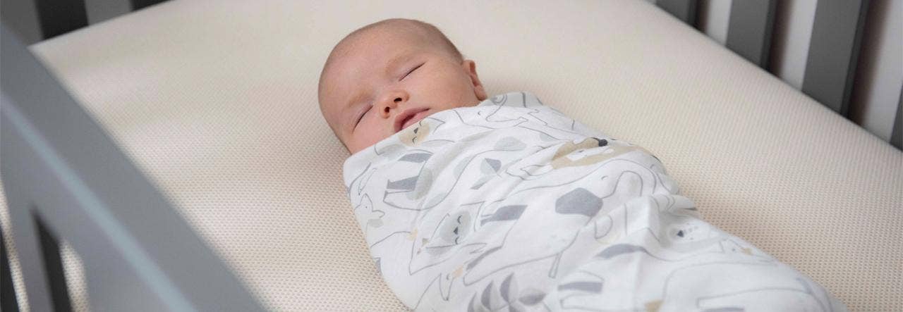 Baby swaddled and sleeping peacefully on an organic mattress