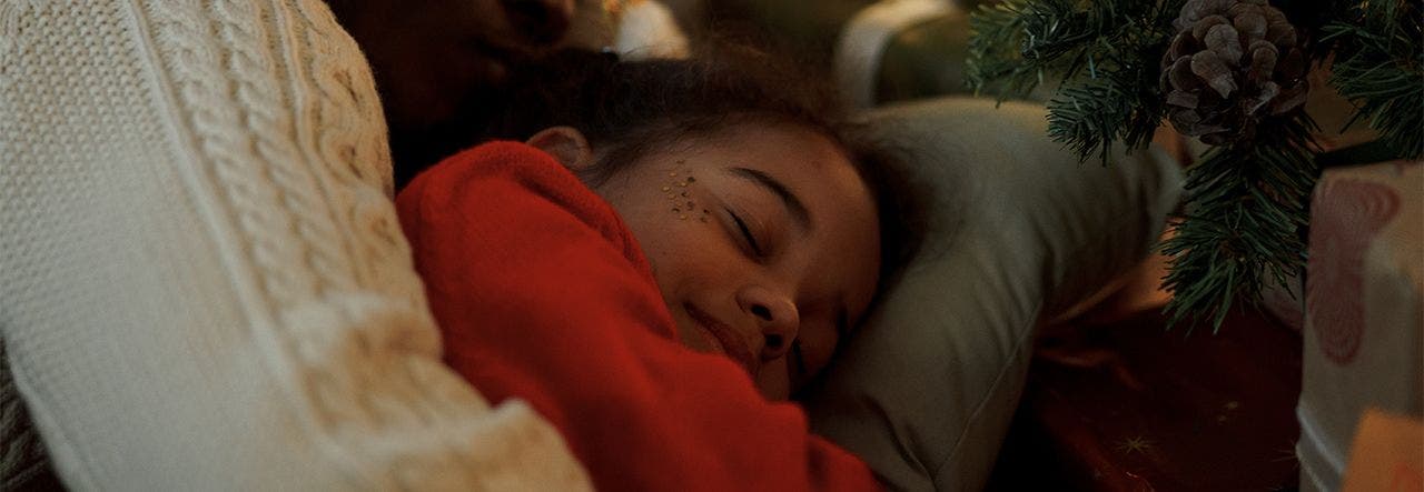 Mother hugging child goodnight with holiday decorations in the background