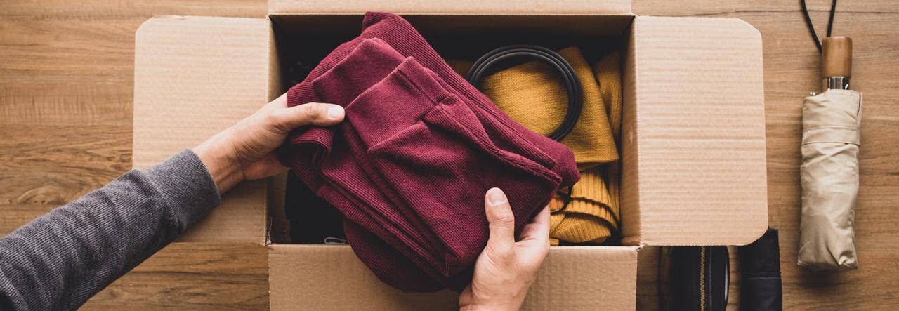 Overhead image of a woman organizing clothing donations in a cardboard box