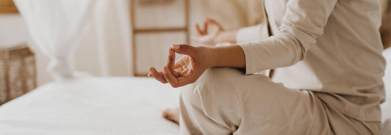 Woman sitting cross-legged on her bed and meditating