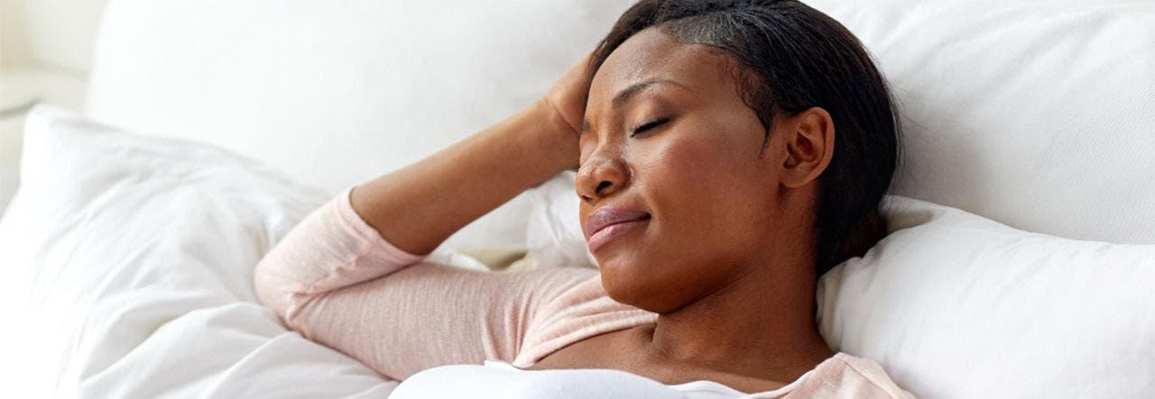 Pregnant woman propped up on pillows, trying to sleep