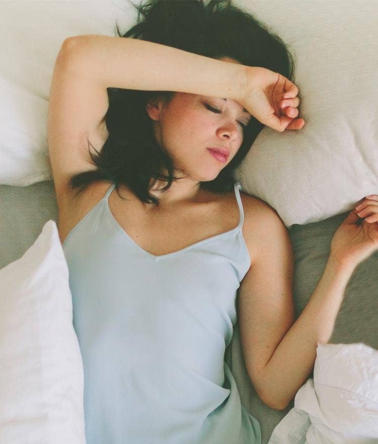 Woman in light tank top trying to sleep cooler at night