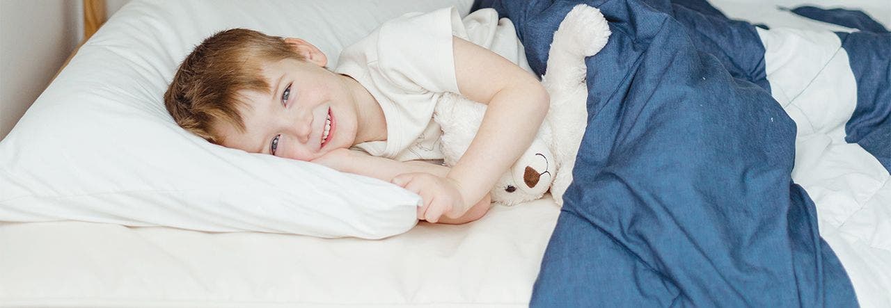 Small boy lying on a twin bed and smiling