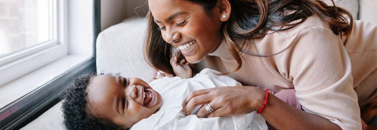 Smiling mother snuggling with her toddler in bed