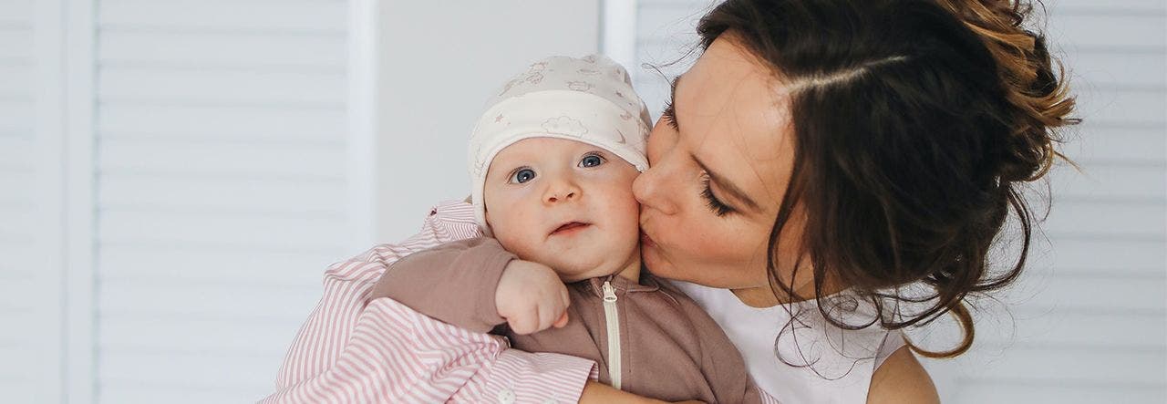 Mother holding her baby and kissing them on the cheek