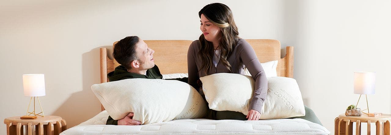 Couple relaxing on their bed with Naturepedic organic pillows