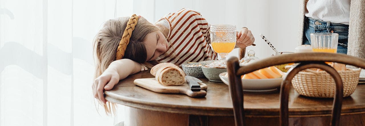 Tween girl half asleep with her head on the kitchen table