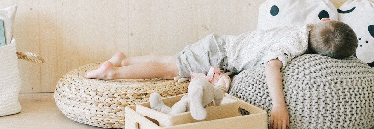 Young boy sleeping on his stomach on a beanbag chair during the daytime