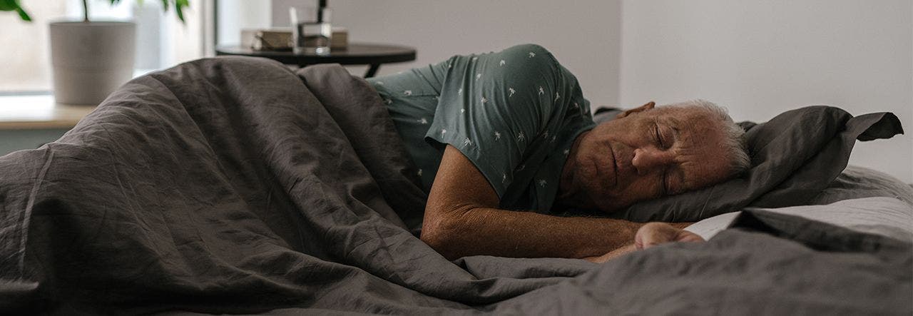 Elderly man sleeping on his side in bed