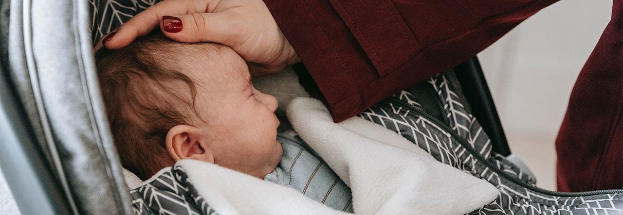 Parent tucking their newborn into the carseat on a cold day