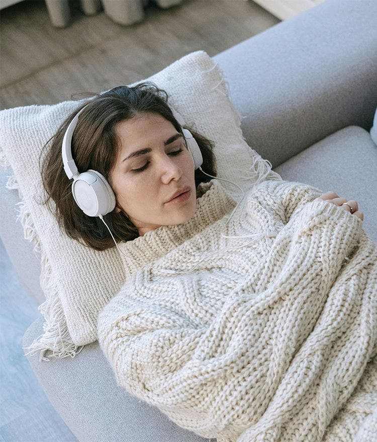 Woman with headphones listening to white noise on a Naturepedic mattress