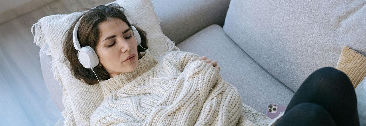 Woman with headphones listening to white noise on a Naturepedic mattress