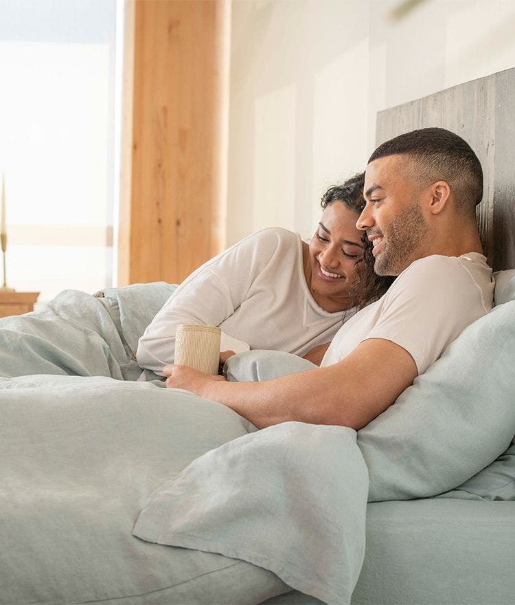 couple cuddling in bed with blue bed sheets