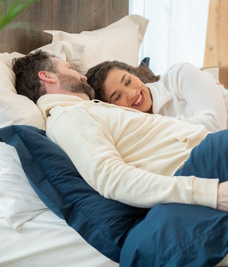 couple cuddling in bed on percale sheets