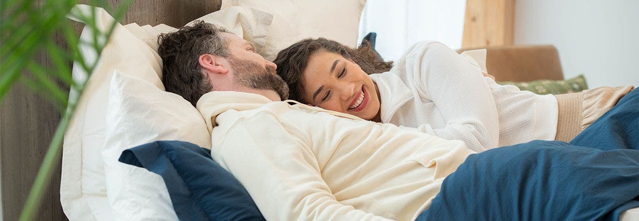 couple cuddling in bed on percale sheets