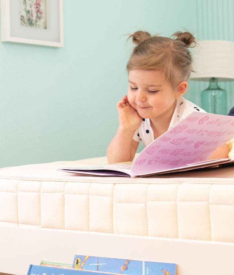 little girl reading on naturepedic verse mattress