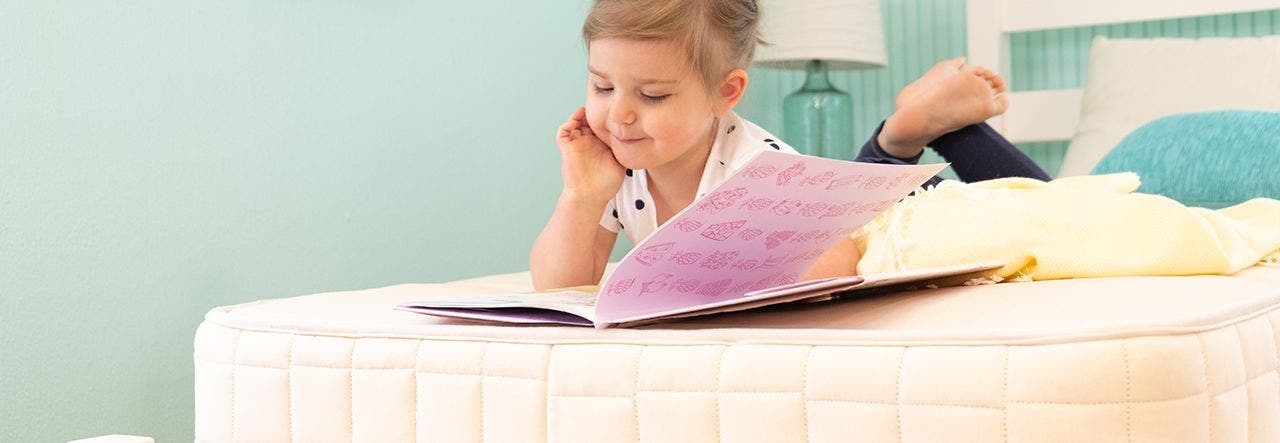 little girl reading on naturepedic verse mattress