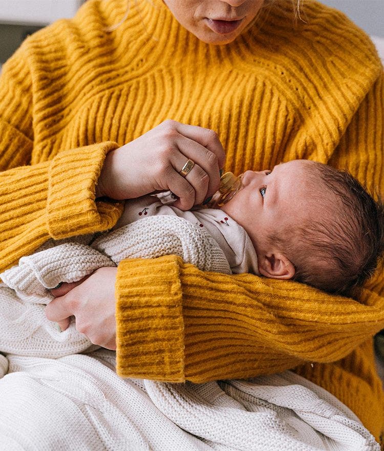 baby being held by parent in yellow sweater