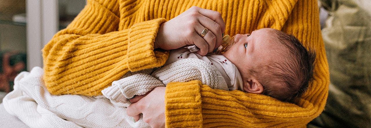 baby being held by parent in yellow sweater