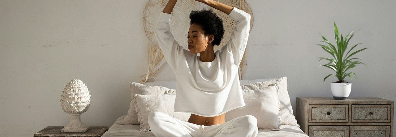 Refreshed woman sitting up in bed and stretching her arms over her head