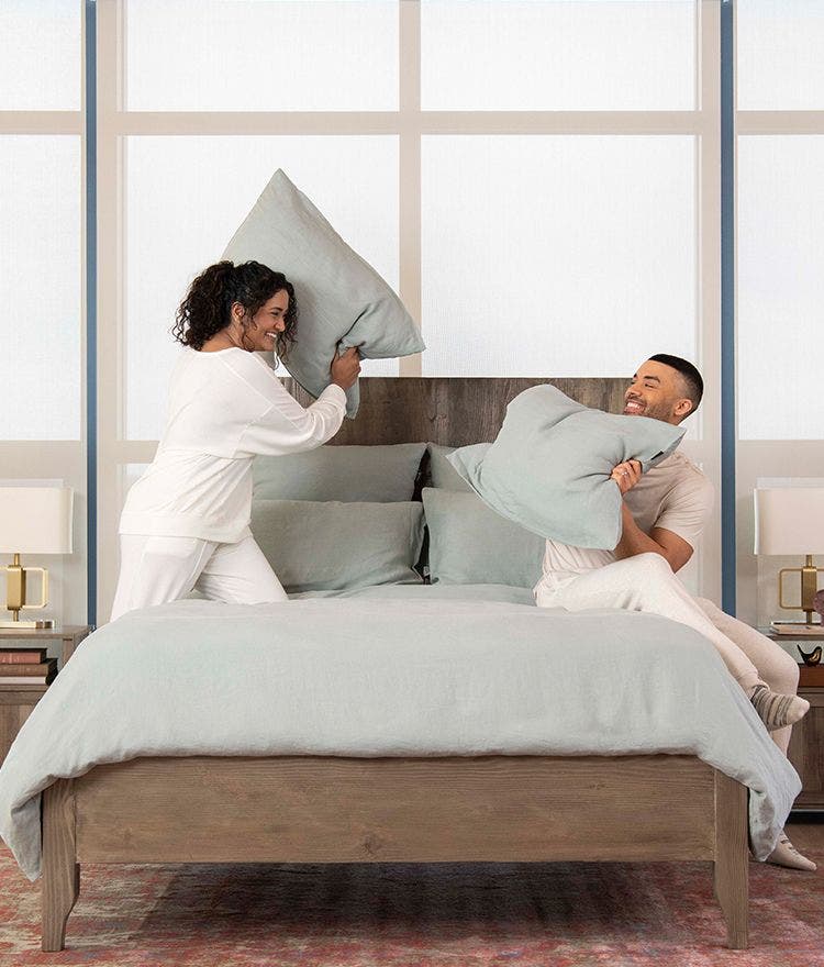 Woman and man pillow fighting in bed