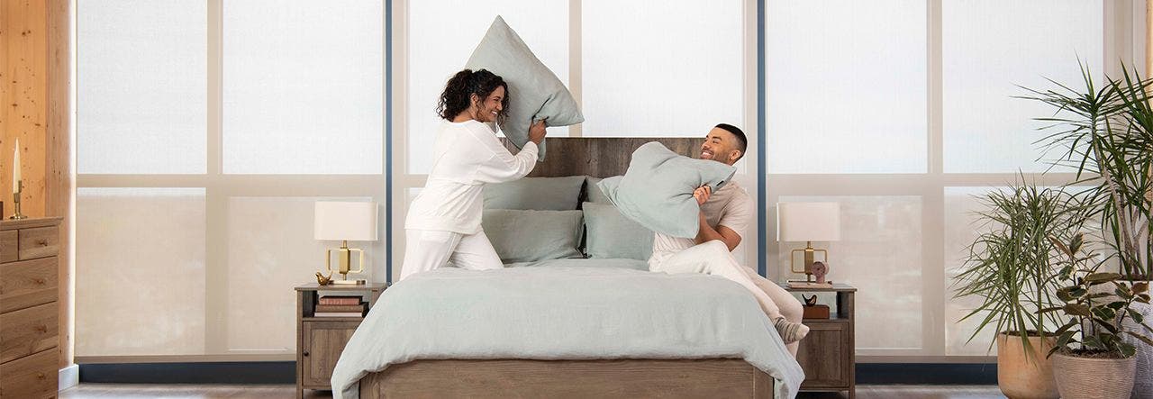 Woman and man pillow fighting in bed