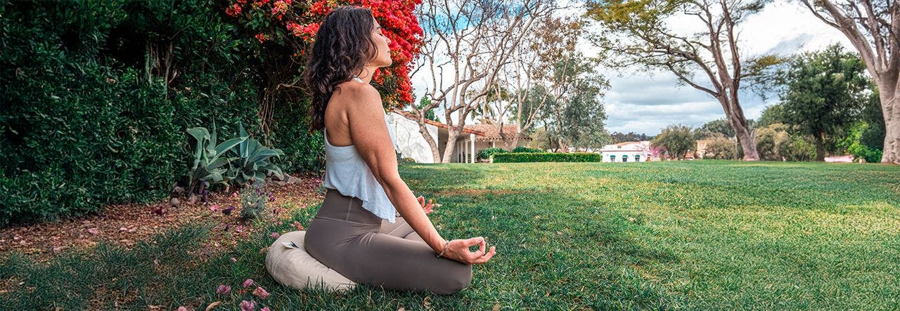 woman meditating outside on a naturepedic meditation cushion