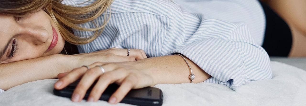 woman holding phone on bed