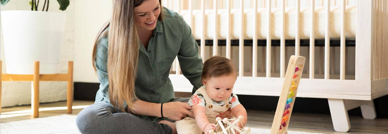 mother and child playing next to naturepedic ultra breathable organic 2-stage crib mattress