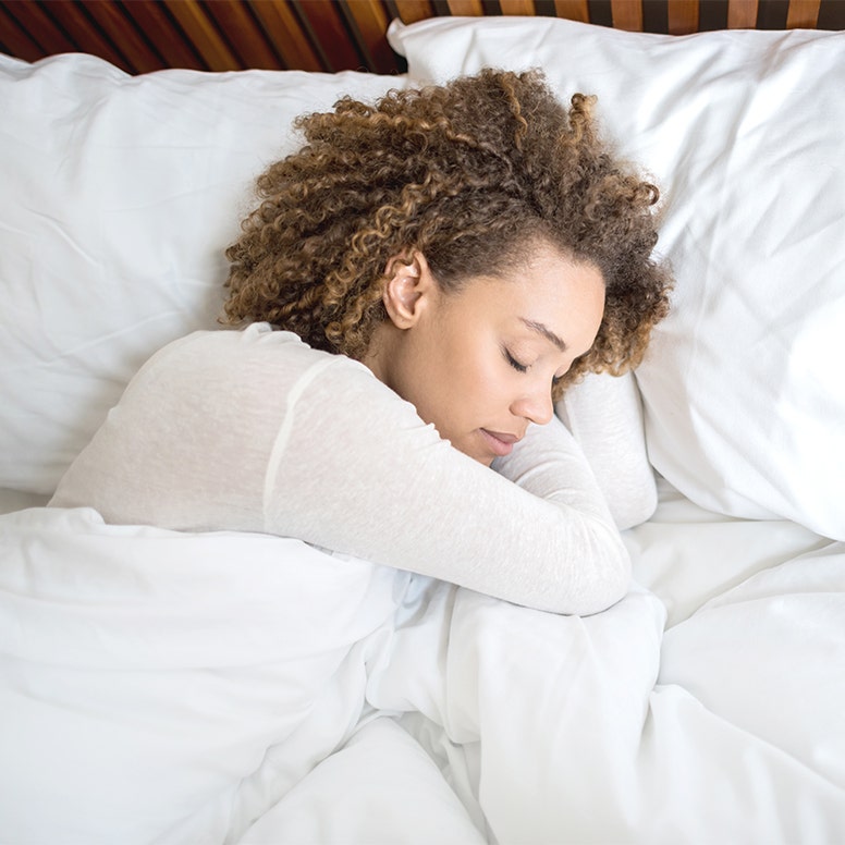 Close-up of woman sleeping in bed snuggling blanket