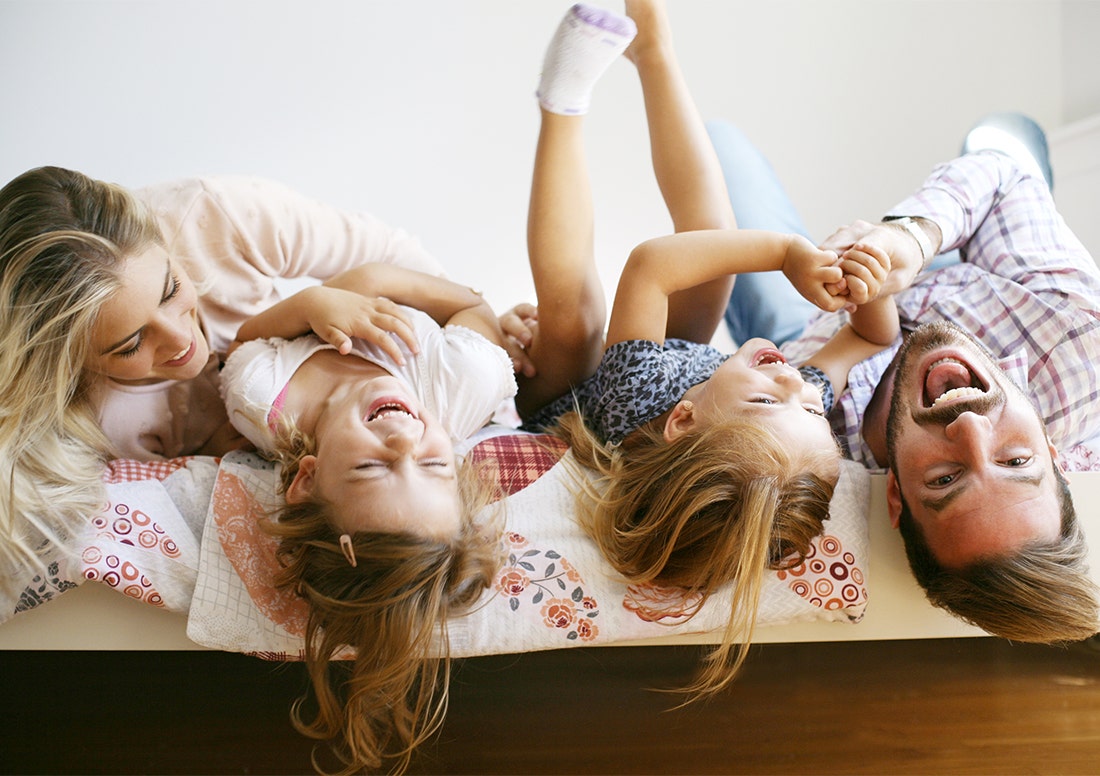 Happy family laughing together hanging over the mattress side