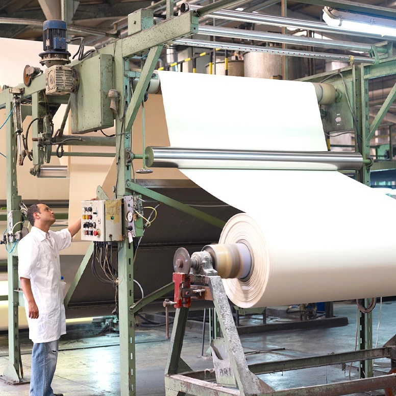 Worker in factory operating fabric processing equipment