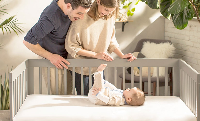 Mom and dad smiling at baby in crib