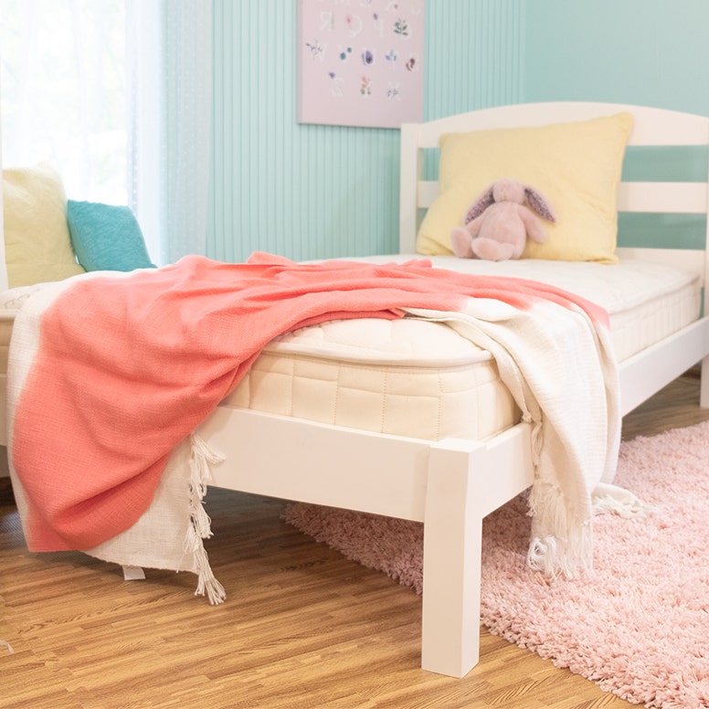 Twin mattress in kids room with blanket hanging over