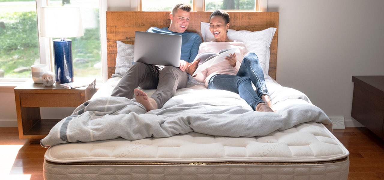 Couple sitting up in bed looking at a laptop 