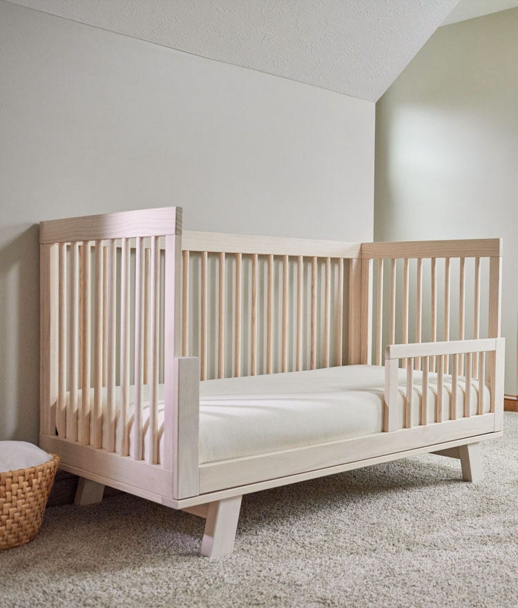 Wooden crib with a Naturepedic crib mattress in a cream-colored room